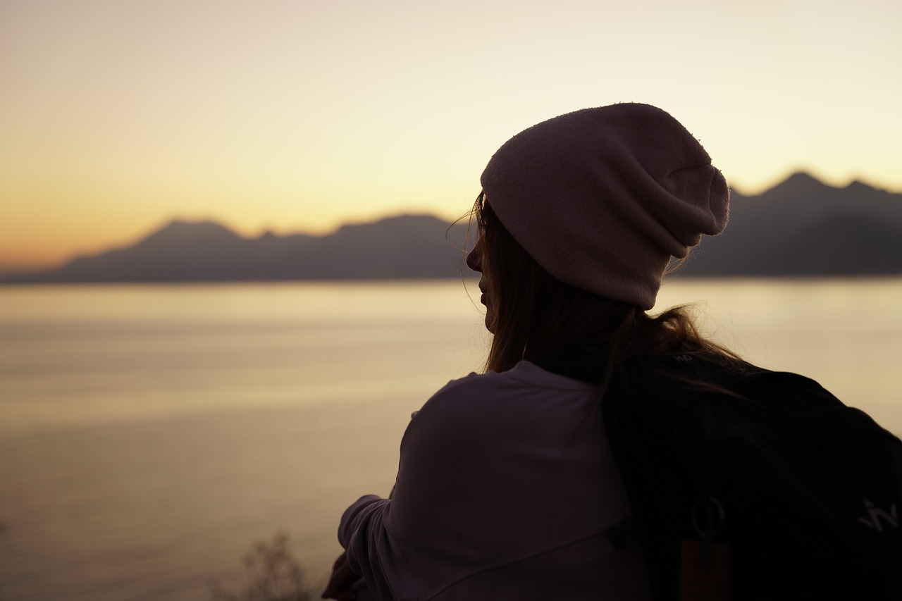 Woman contemplating by a lake during sunset